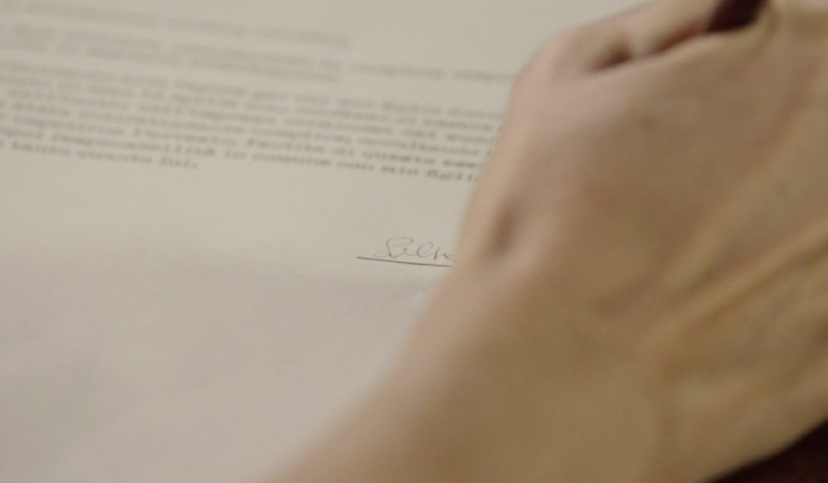 Elodie Treccani (Silvana) mentre firma un documento in un flashback di una scena della puntata 148 de “Il Paradiso Delle Signore 8”. Credits: Rai.